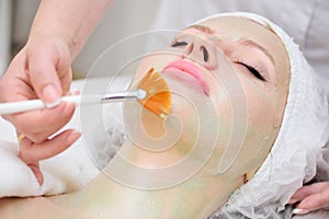 A cosmetologist performs an enzyme therapy procedure for a female patient.