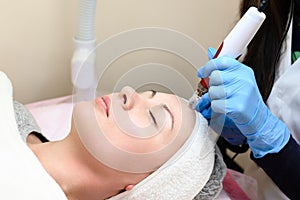 A beautician performs a rejuvenating mesotherapy procedure using dermapen. photo