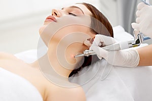 Cosmetologist removing mole with laser machine