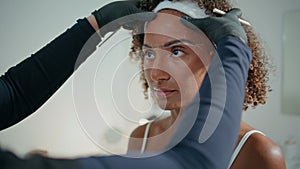 Cosmetologist shaping woman brows in beauty salon closeup. Curly girl visiting