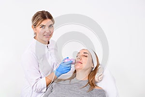 Cosmetologist with a smile makes a electric salon procedure for a beautiful woman