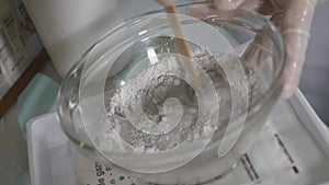 Cosmetologist squeezes cream from a tube on a glass saucer. Hands in medecine gloves