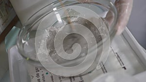 Cosmetologist squeezes cream from a tube on a glass saucer. Hands in medecine gloves