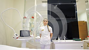 A cosmetologist-therapist stands in a beauty salon and looks into the camera. Anti-cellulite LPG massage in a beauty