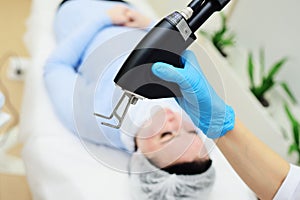 cosmetologist uses a CO2 fractional ablative laser to rejuvenate the skin and remove scars in a modern cosmetic beauty