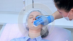 Cosmetologist wiping cream with anaesthetic from face before biorevitalization.