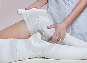 The cosmetologist wraps the leg of the customer. Anti-cellulite procedure