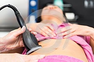 Cosmetology doctor makes a young female client a vacuum massage of the abdomen