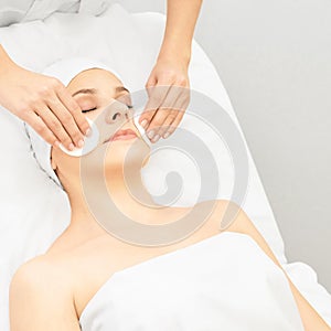 Cosmetology doctor remove mascara from girl face. Cotton pad with woman hands. Demakeup lotion photo