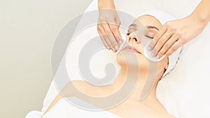 Cosmetology doctor remove mascara from girl face. Cotton pad with woman hands. Demakeup lotion photo