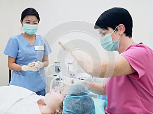 Cosmetology procedure rejuvenation, revitalization, skin nutrition . Doctor with nurse making mask of beauty cream.