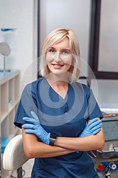 Cosmetology Service. Young doctor in gloves at beauty clinic standing crossed arms smiling confident