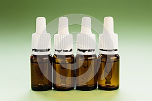 cosmetology, skin care, a row of glass bottles with pipettes and hyaluronic acid inside on a green background