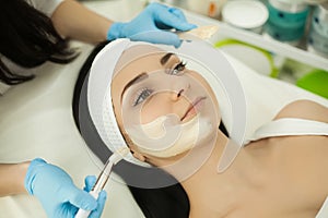 Woman receiving professional brush peeling in the cosmetology of photo