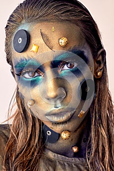 Cosmic unusual makeup with decorative elements on face, golden skin