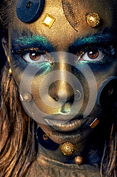 Cosmic unusual makeup with decorative elements on face, golden skin