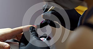 Cosmitologist makes a manicure to a brunette in a hairdressing salon. Woman beautician makes the procedure,applies