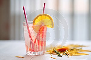 cosmo with pink paper straw, softfocus citrus fruit slices, light background