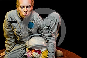 cosmonaut in spacesuit with flowers in helmet sitting