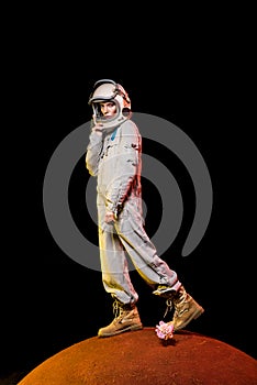 cosmonaut in spacesuit and helmet standing on peony flower