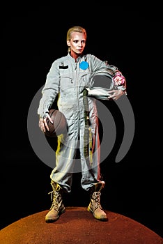 cosmonaut in spacesuit holding basketball ball and helmet with flower while standing on red