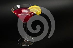 Cosmopolitan cocktail classic drink with ice, decorated with slices of lemon and orange on black background.