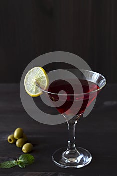 Cosmopolitan cocktail. Martini glass with cocktail and olives on black background.