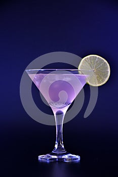 Cosmopolitan cocktail, a refreshing drink in a tall glass with ice and a slice of lemon on a black background