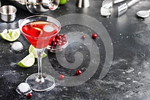 Cosmopolitan cocktail with vodka, liqueur, cranberry juice, lime, ice and orange zest, gray bar counter background, bartender