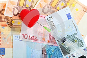 Cost of health care: red heart syringe on euro money