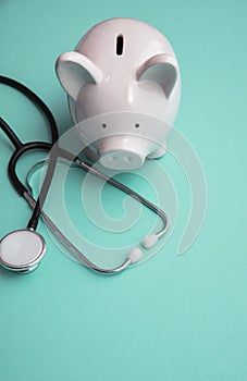 Cost of healthcare. Piggy bank money box with a medical doctors stethoscope