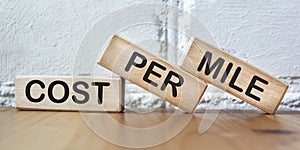 COST PER MILES text on wood block, white brick wall background
