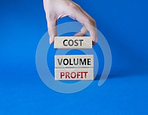 Cost Volume Profit symbol. Concept word Cost Volume Profit on wooden blocks. Businessman hand. Beautiful blue background. Business