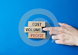 Cost Volume Profit symbol. Concept word Cost Volume Profit on wooden blocks. Businessman hand. Beautiful blue background. Business