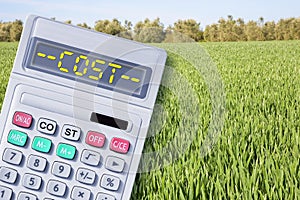 Cost of wheat and cereals - concept with calculator against a green corn agricultural field in springtime still without the ear