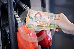 Costa Rica, gas station, woman holding a handful of money by the car, Concept, Rising fuel prices, Refueling cars, Inflation in