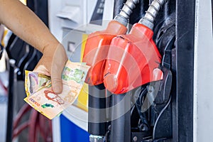 Costa Rica, gas station, woman holding a handful of money by the car, Concept, Rising fuel prices, Refueling cars, Inflation in