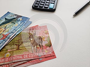 Costa Rican banknotes, black  pen, calculator and white background