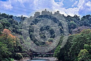 Costa Rican mountains and bridge over a river during dry season.