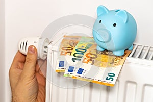 costs of heating apartments in winter in the European Union, energy and economic concept, hand unscrewing the radiator, piggy bank