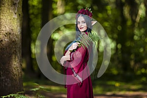 Costume Play Ideas. Forest Sprite in Flowery Garland Posing with Elf Enlarged Ears in Summer Forest With Fern Leaves