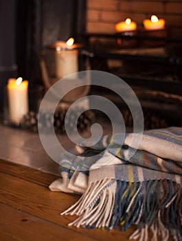 Cosy blanket nearby fire place with candles