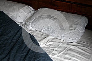 cosy Interior with white bed linen. Bedroom with oak bed, grey and blue bedding, and bedside table