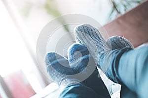 Cosy relaxing in the wintertime at home: Couple with woollen socks is lying on the couch