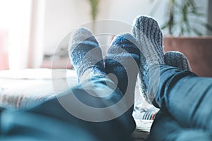 Cosy relaxing in the wintertime at home: Couple with woollen socks is lying on the couch