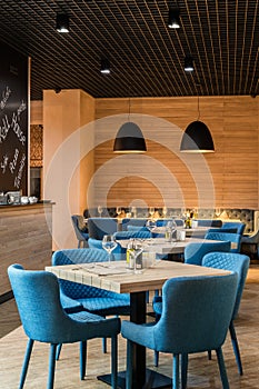 Cosy restaurant european style modern interior with blue chairs and wine glasses on tables , vertical shot