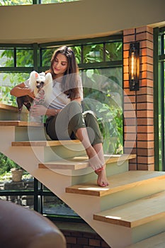 Cosy room in big house, interior design, stairs. Beauty model girl portrait with little chinese crested dog sitting on stairs