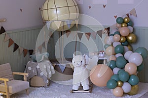 cosy room corner decorated for baby girl first birthday with balloons, swing hoarse, flags and toys