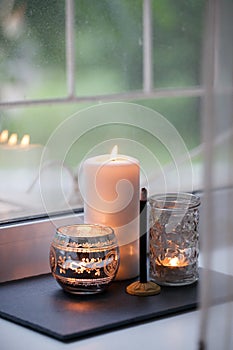 Cosy and soft winter autumn home background, karoma stick and candles on an stone board on windowsill. Christmas or seasonal