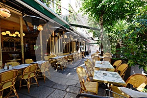 Cosy street with round tables and bright chairs of traditional outdoor French cafe in Paris
